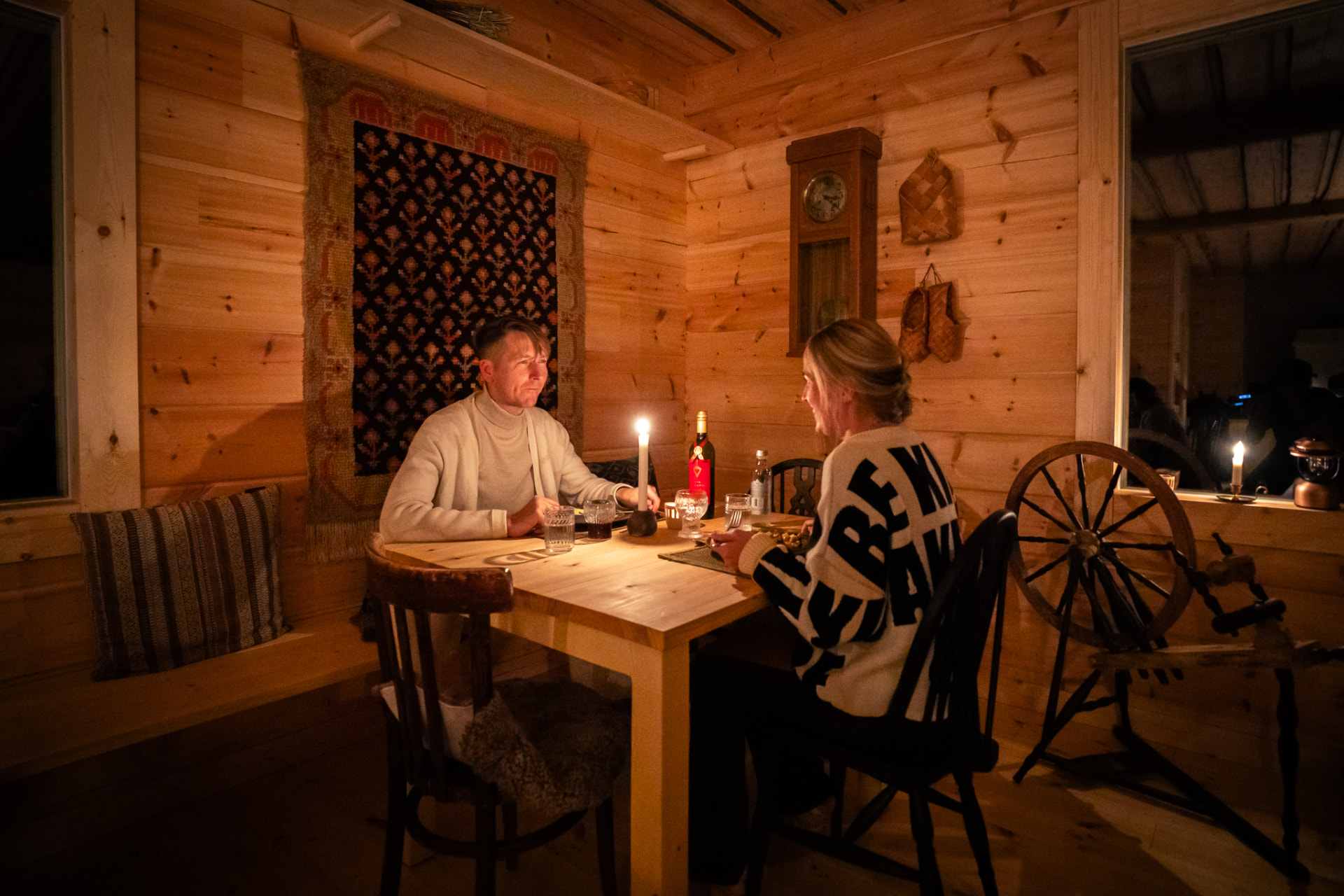 Two guests sharing a candlelit meal at a wooden table in the main cabin