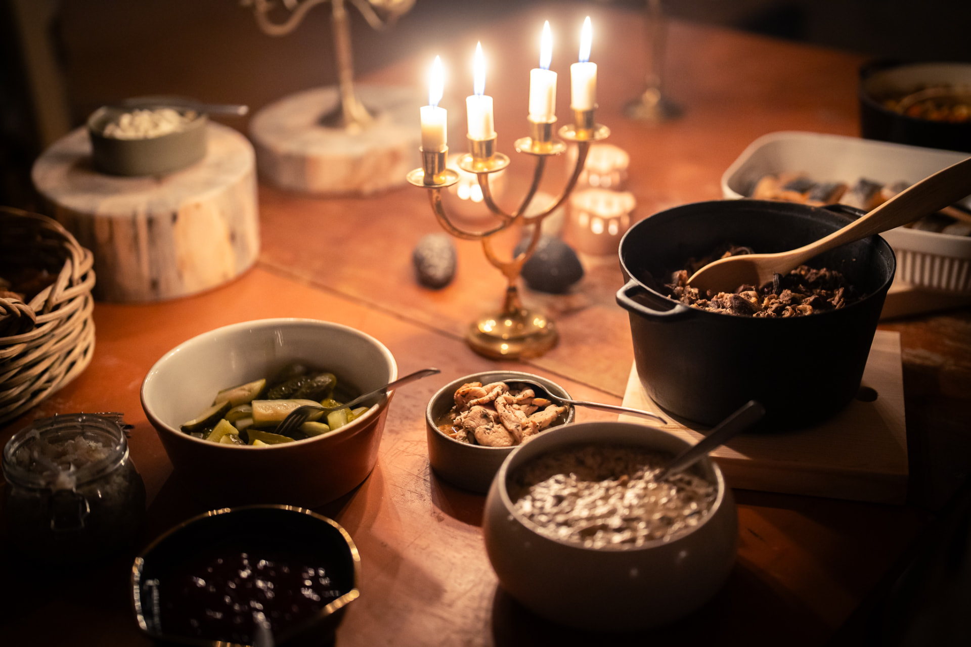 A candlelit spread of local dishes arranged around a brass candelabra on a wooden table