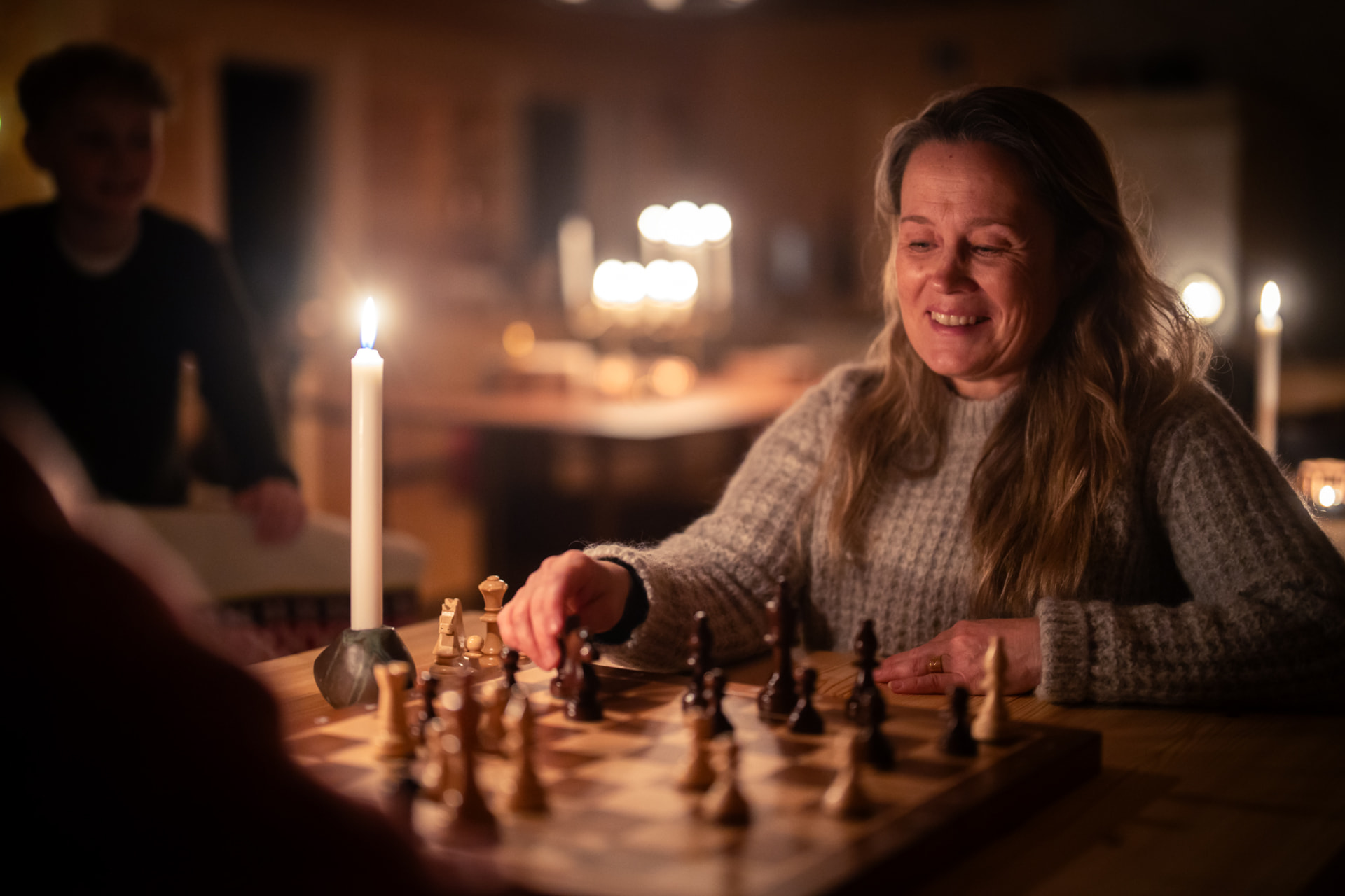 A guest smiling over a chessboard by candlelight